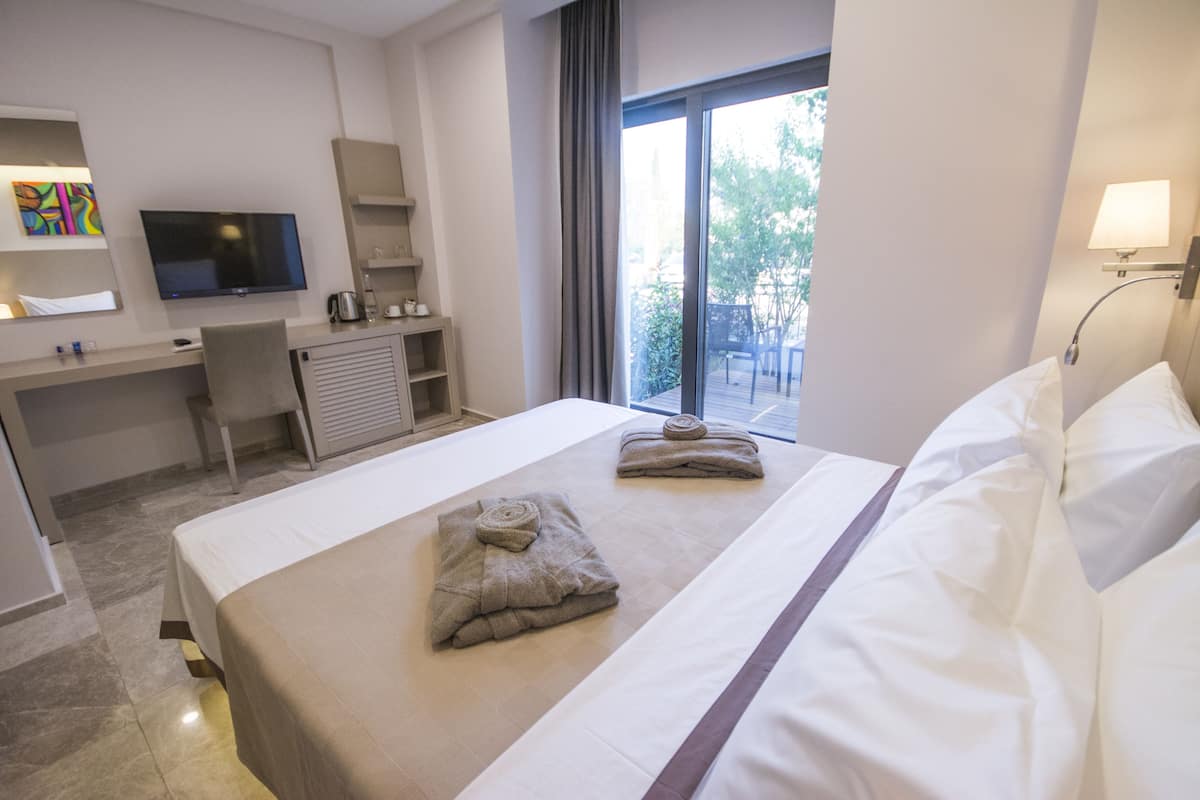 A hotel room with a bed, a desk, a television, and a window with a view of the outdoors.