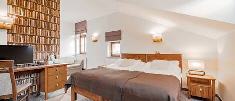 A bedroom with a large bookshelf, a desk, a bed, and a window.