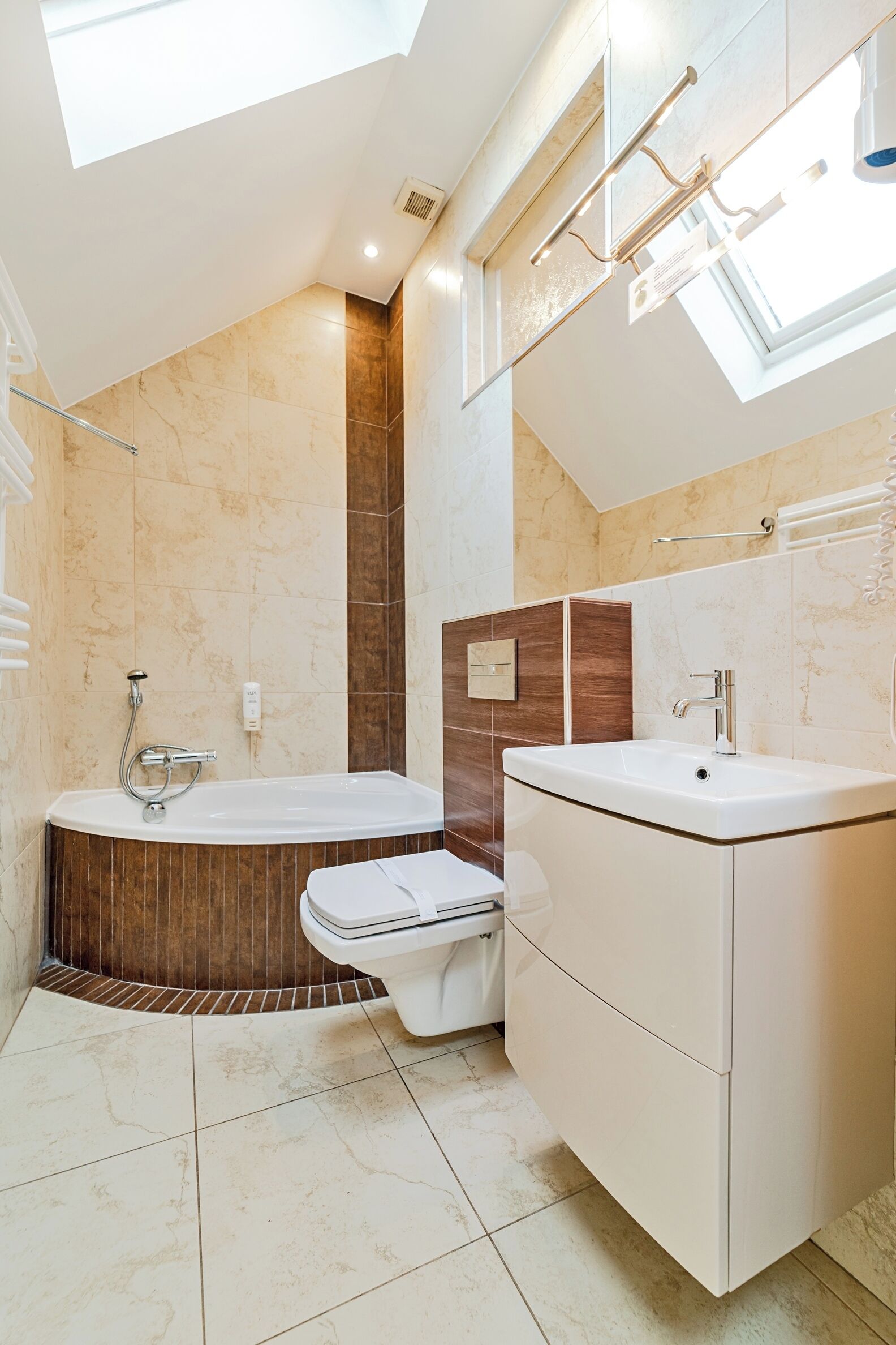 Un baño moderno con tragaluz, una bañera, un inodoro y un tocador.