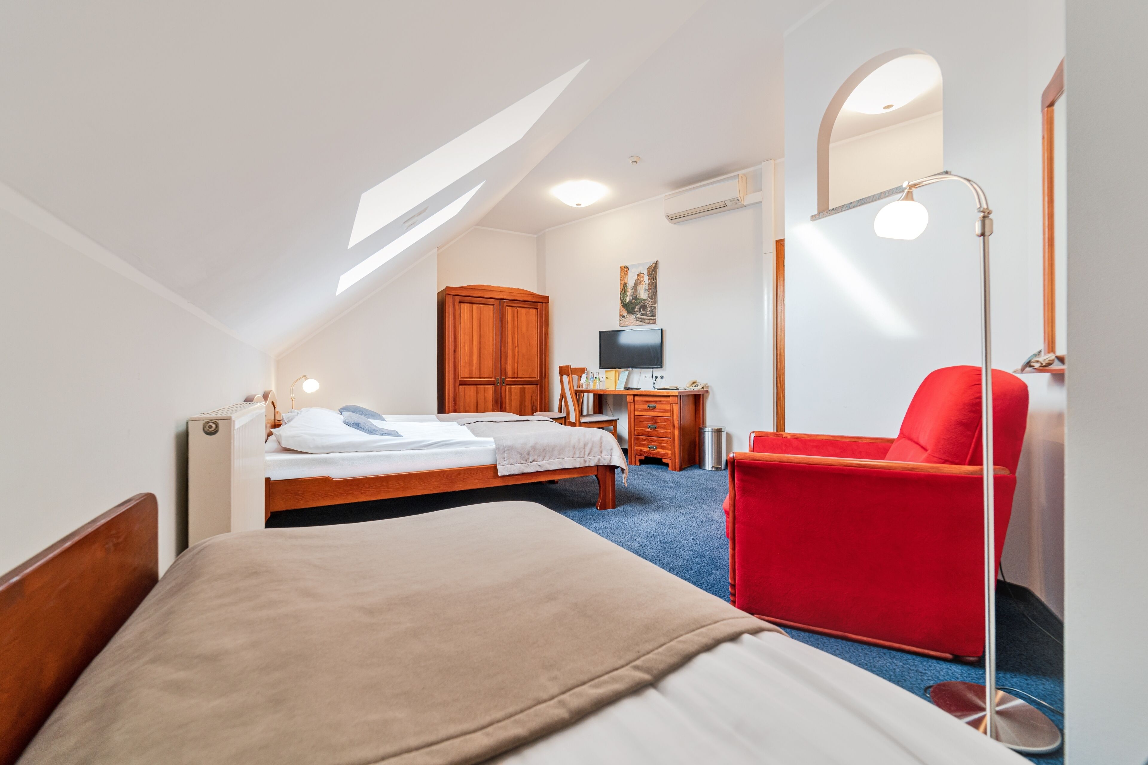 Een hotelkamer met een bed, een bureau, een stoel, een televisie en een kledingkast.