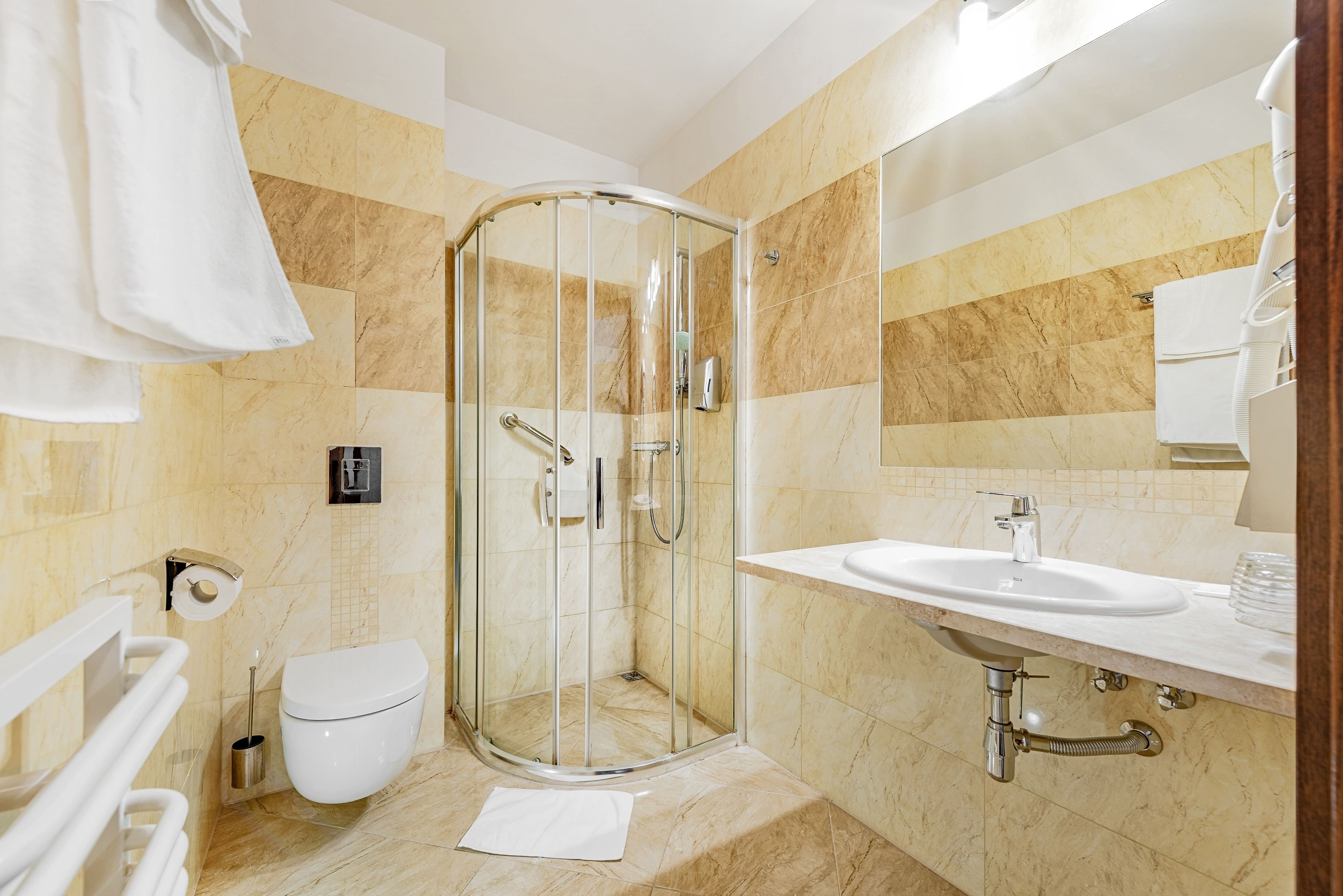 A modern bathroom with a glass shower enclosure, a toilet, and a sink with a mirror above it.