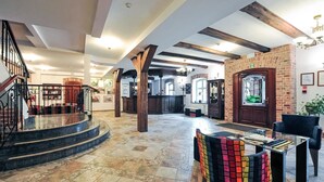 A spacious lobby with a marble staircase, a reception desk, and a seating area with colorful chairs. - Hotel Młyn (Elblag)