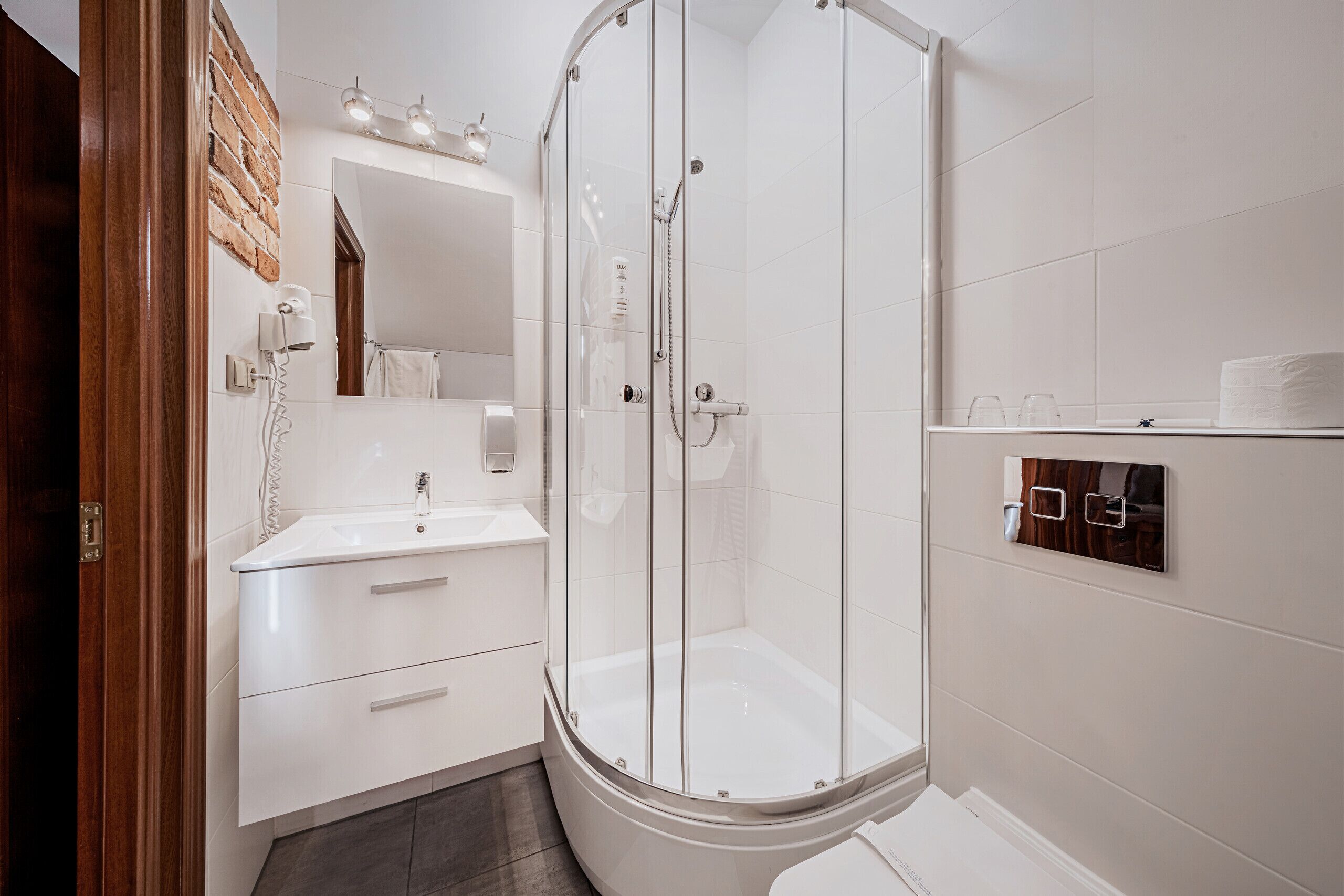 A modern bathroom with a glass-enclosed shower, a white sink, and a mirror above it.