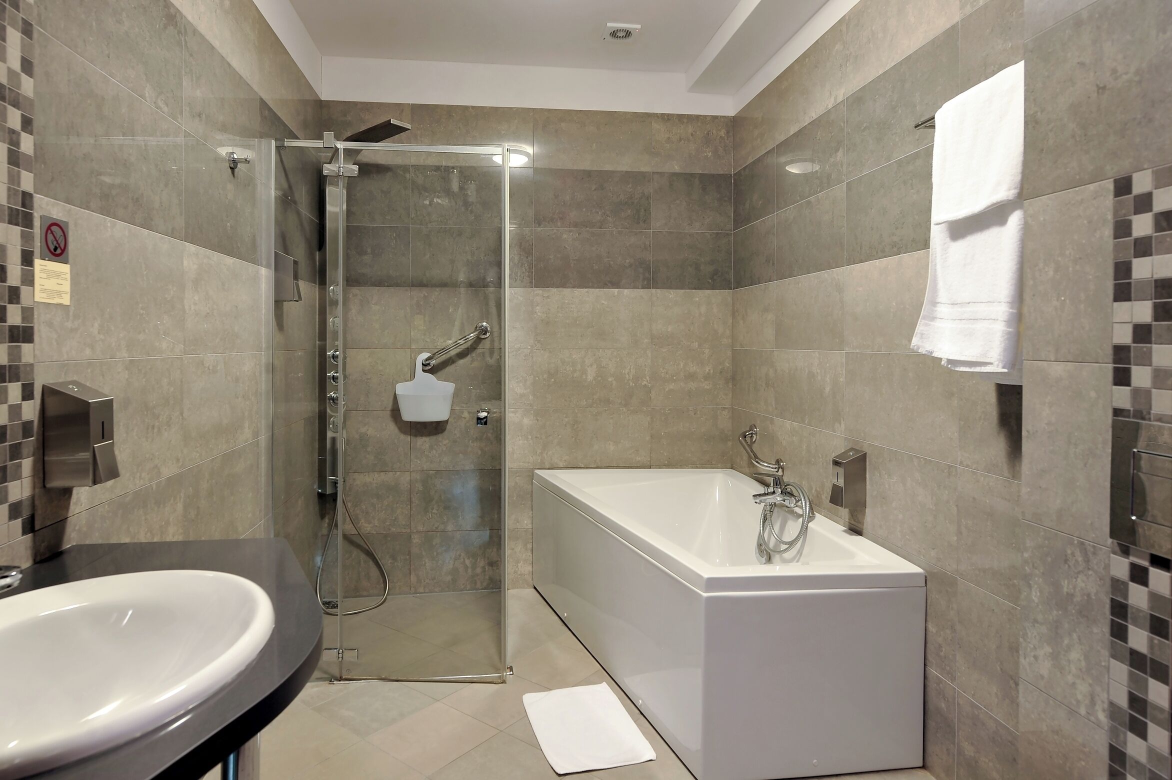 Un baño moderno con ducha de vidrio, una bañera independiente y un lavabo.
