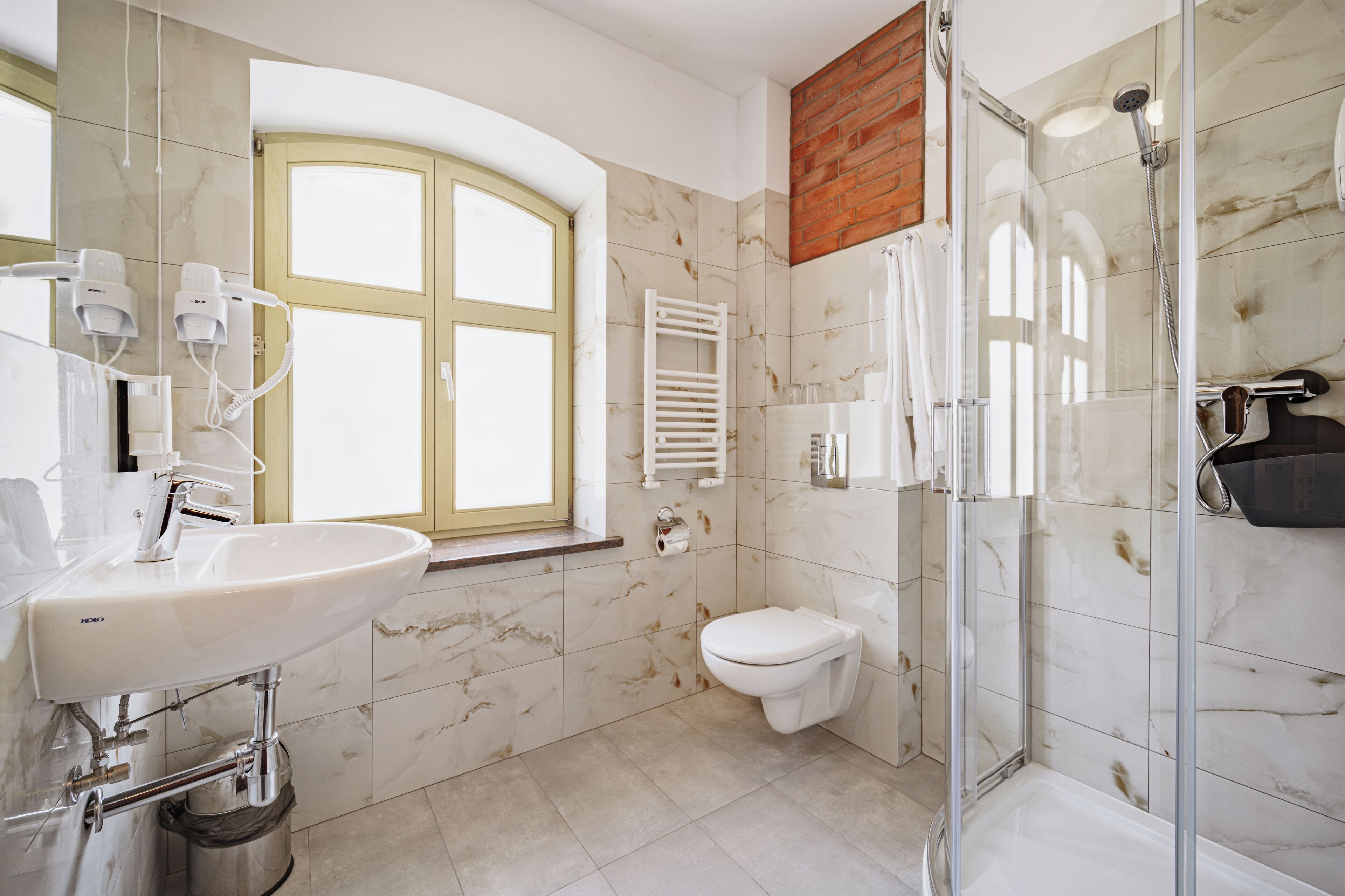 Un baño moderno con lavamanos, inodoro y cabina de ducha de vidrio.