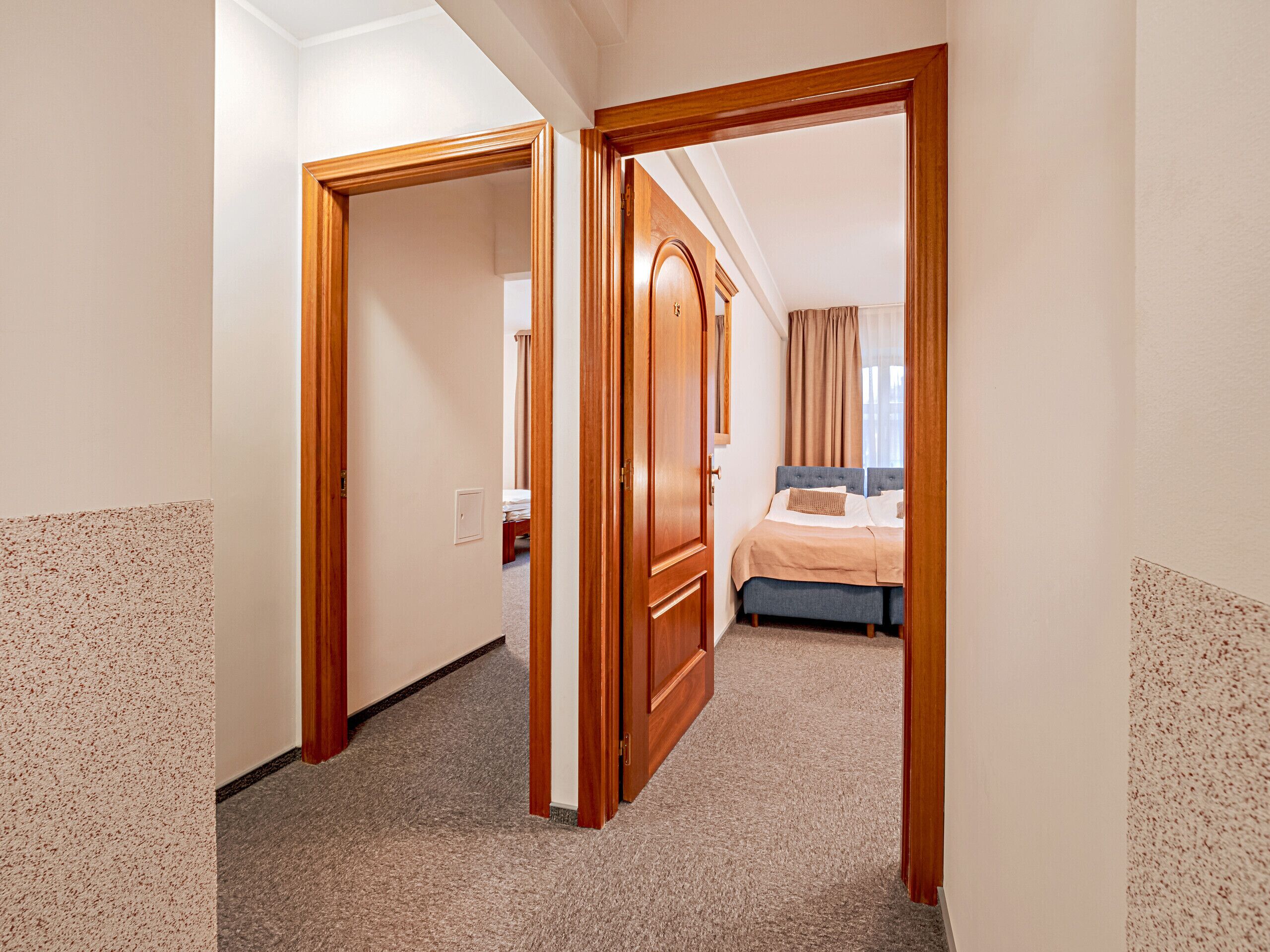 Une chambre d’hôtel avec un lit, une armoire en bois et un sol recouvert de moquette.
