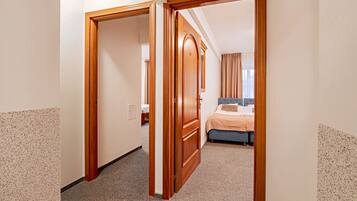 Une chambre d’hôtel avec un lit, une armoire en bois et un sol recouvert de moquette.