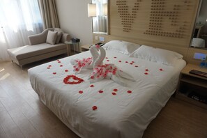 Habitación de hotel con una cama grande, un sofá, una mesita de noche y un panel decorativo en la pared.
