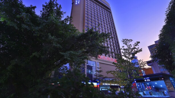 Un hotel de gran altura con varios pisos, ventanas amplias y una entrada destacada.