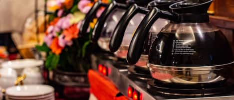 A coffee station with multiple kettles and a coffee pot, a flower arrangement, and a sign labeled "BOX".