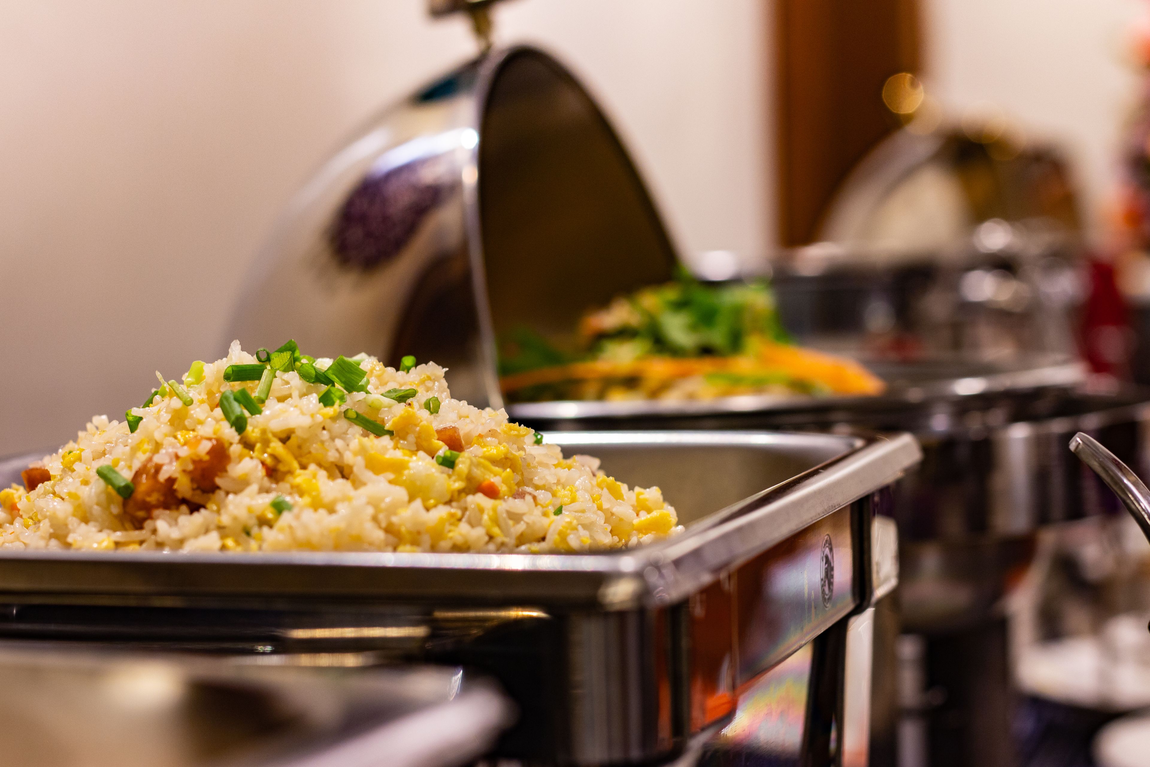 Un bufé con diversos platos, incluyendo arroz frito decorado con cebollas verdes.