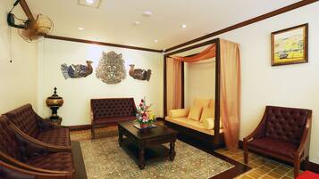 A room with a sofa, two armchairs, a coffee table, and a decorative wall piece.