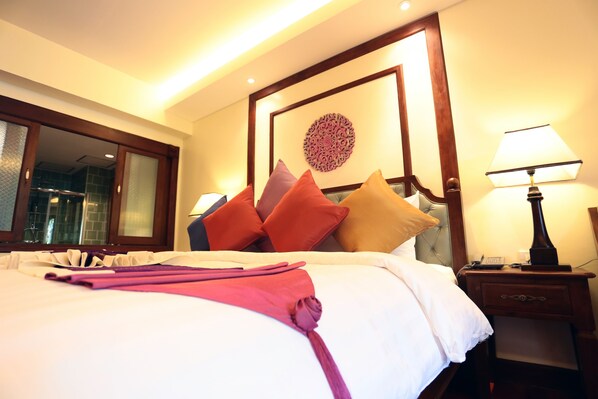 Una habitación de hotel con una cama bien hecha, una mesita de noche con lámpara y un elemento decorativo en la pared.