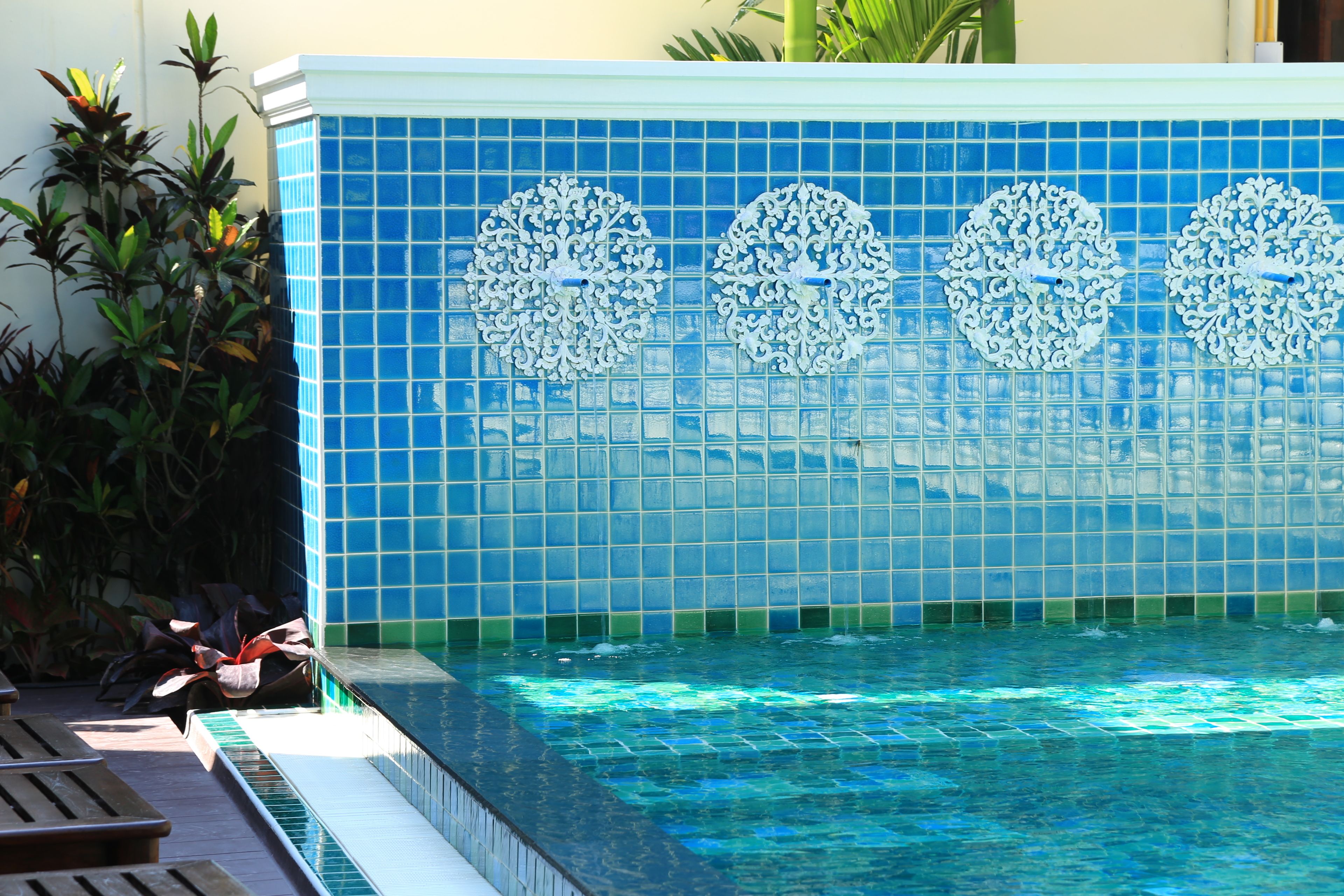 Une piscine agrémentée de carreaux décoratifs et dotée d’un espace avec des bancs.