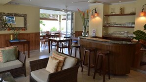 A hotel lobby with a bar area, dining tables, and wicker furniture. - Hotel Bel Air (Mahé Island)