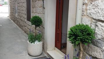A stone building with a wooden door, potted plants, and a colorful doormat.
