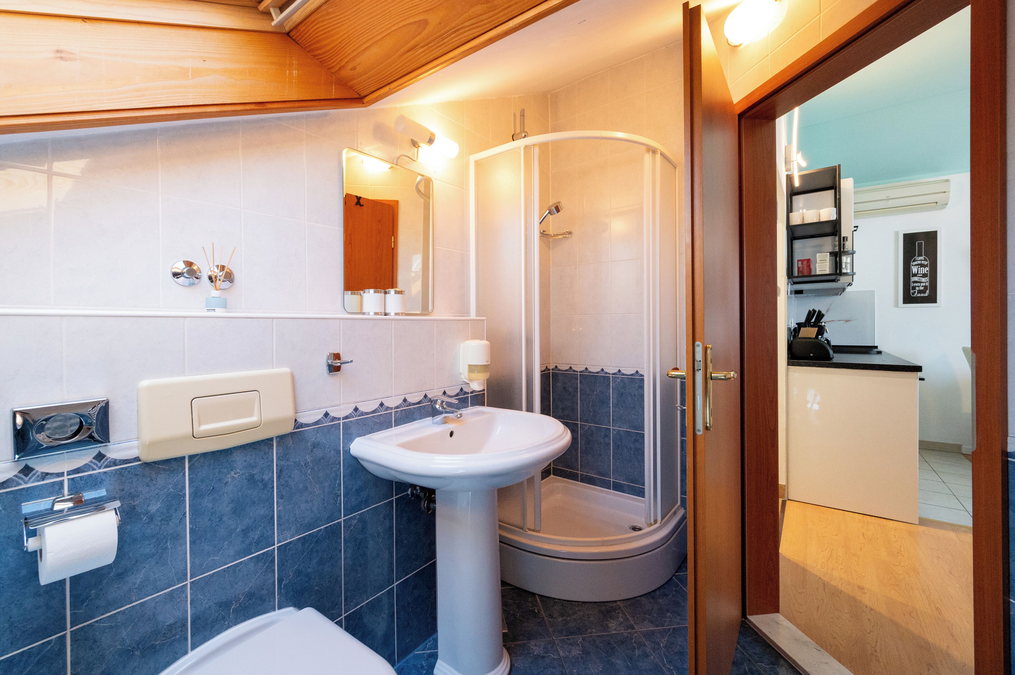A bathroom with a white sink, a glass shower enclosure, and a wooden ceiling.