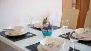 A dining table set with plates, cutlery, and glasses, with a decorative vase in the center.