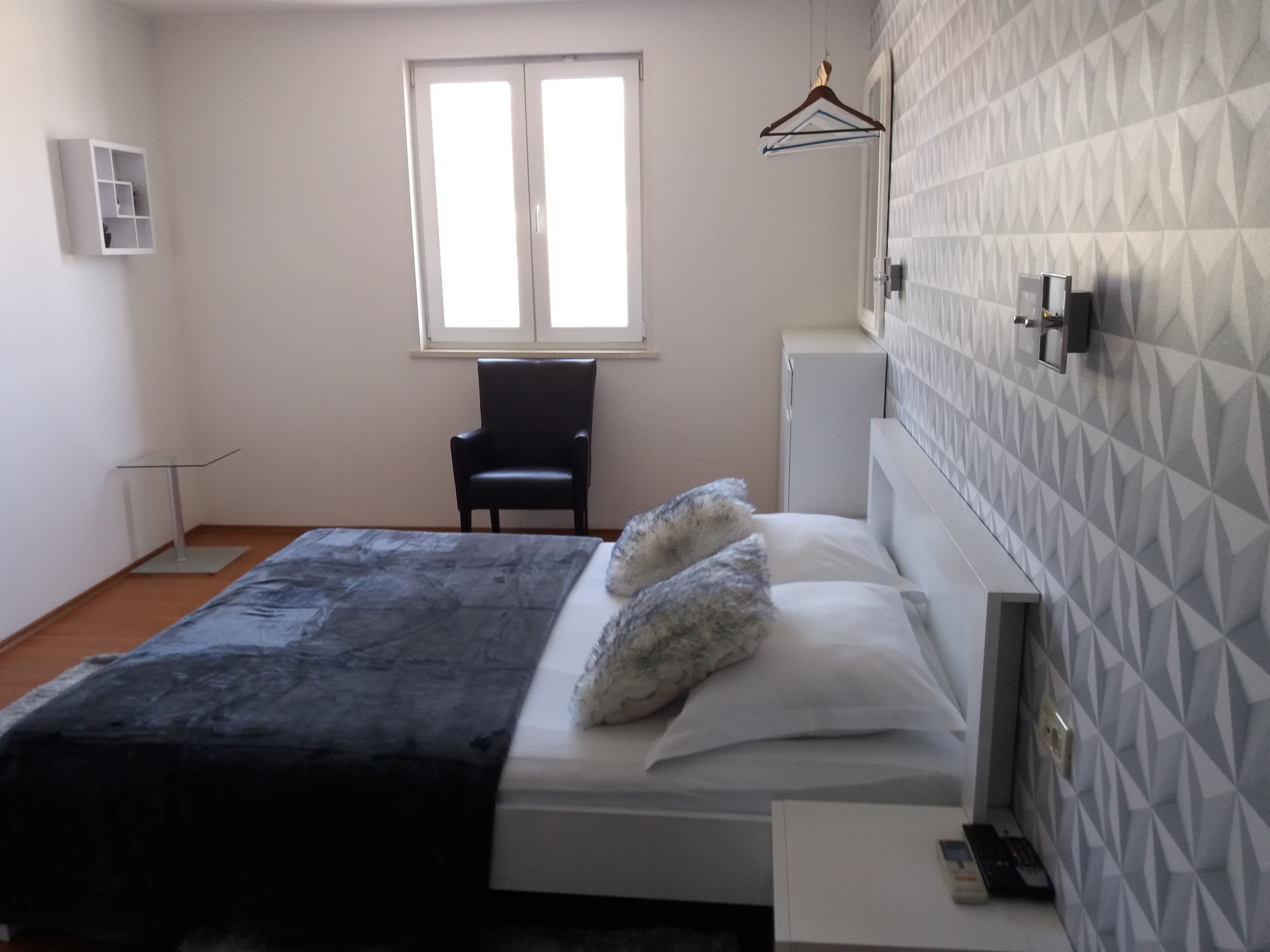 Un dormitorio con cama, una silla, un escritorio y un armario.