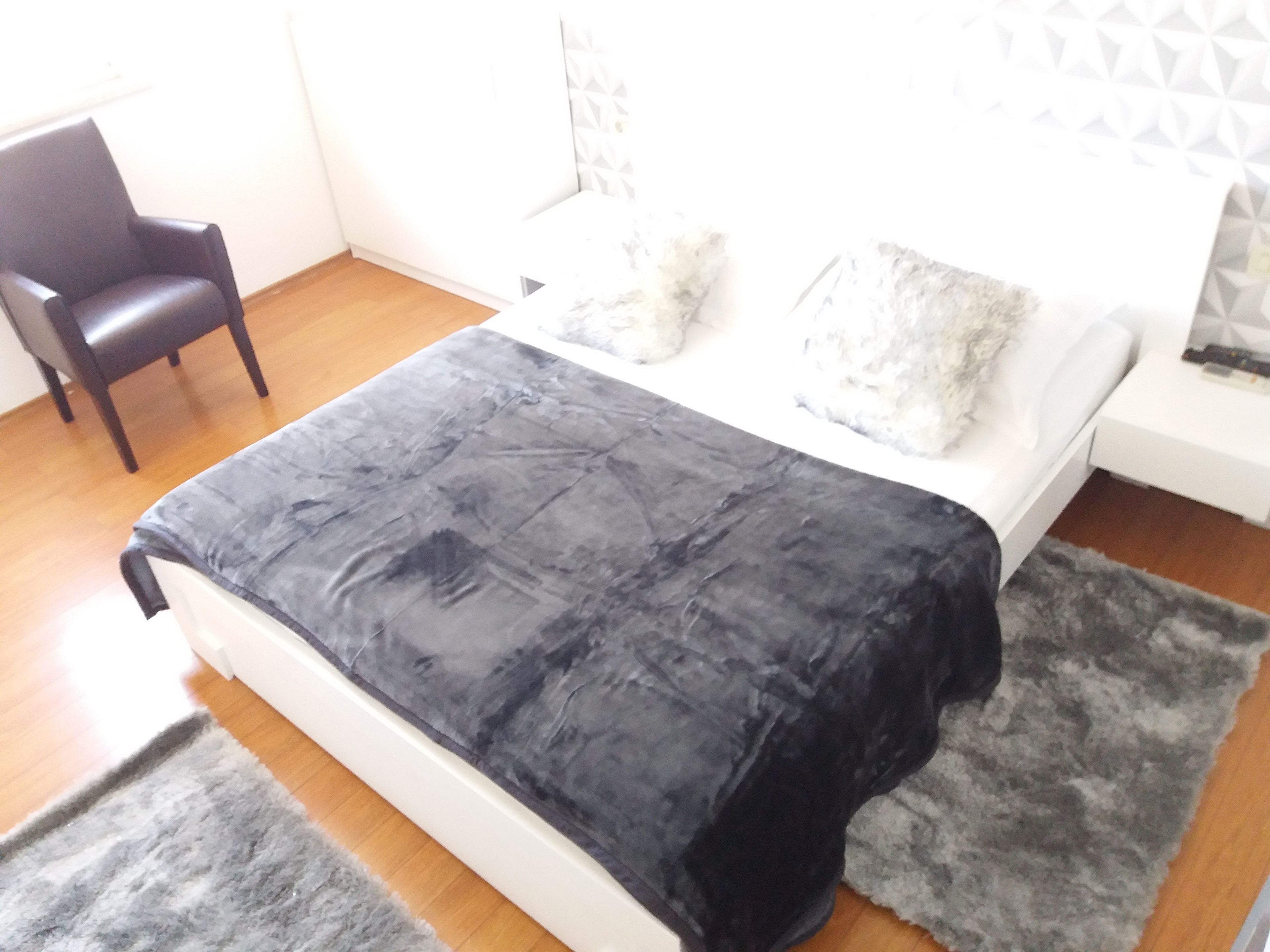 Un dormitorio con cama, una silla y un papel tapiz estampado.