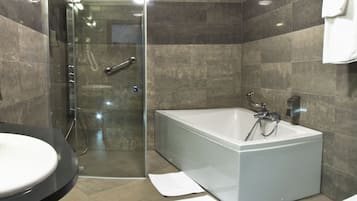 Un baño moderno con ducha de vidrio, bañera independiente y tocador con lavabo.
