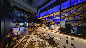 Zona de bar con taburetes, una barra y piso de baldosas.