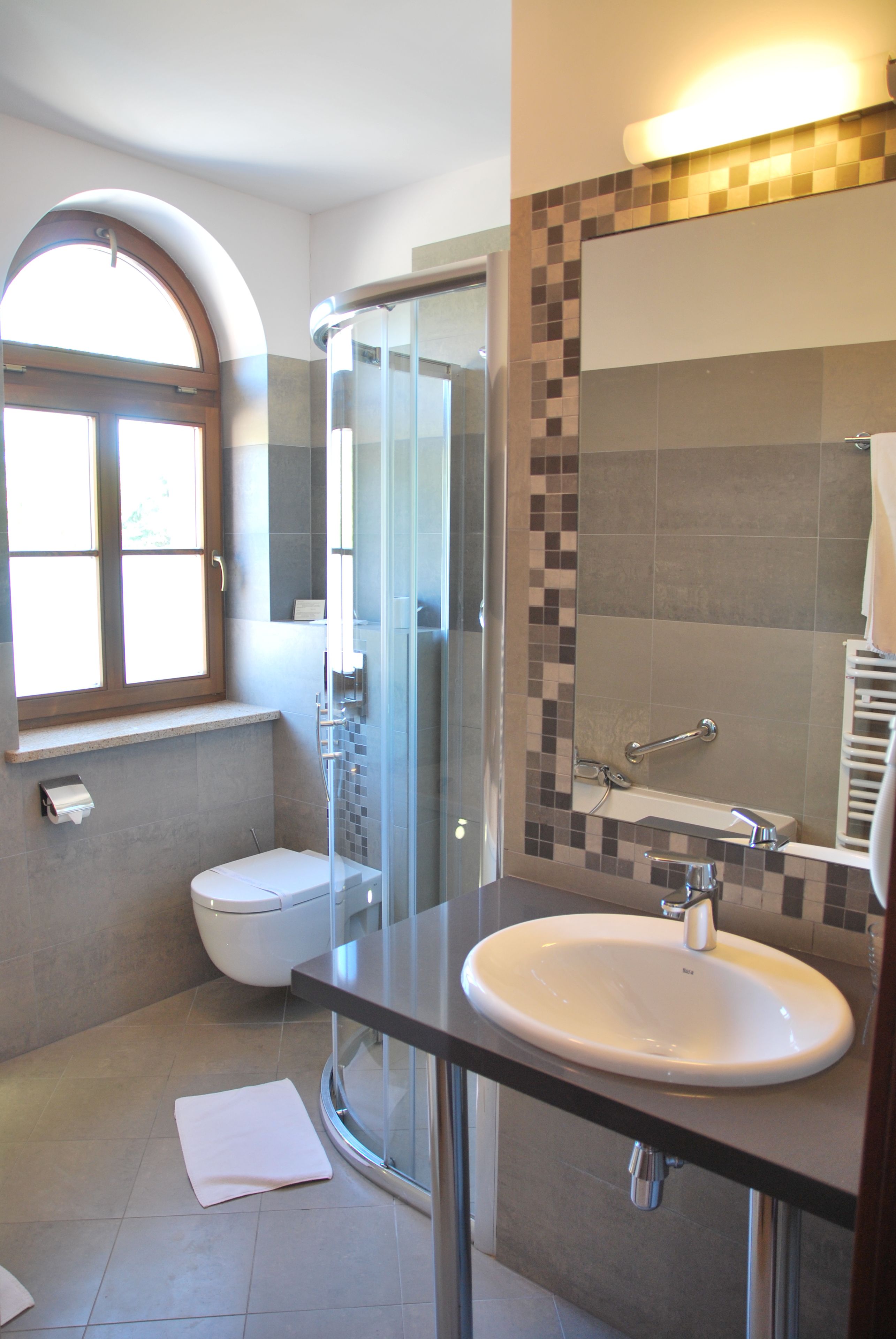 Un baño moderno con ducha envuelta en cristal, un lavabo blanco y un espejo grande.