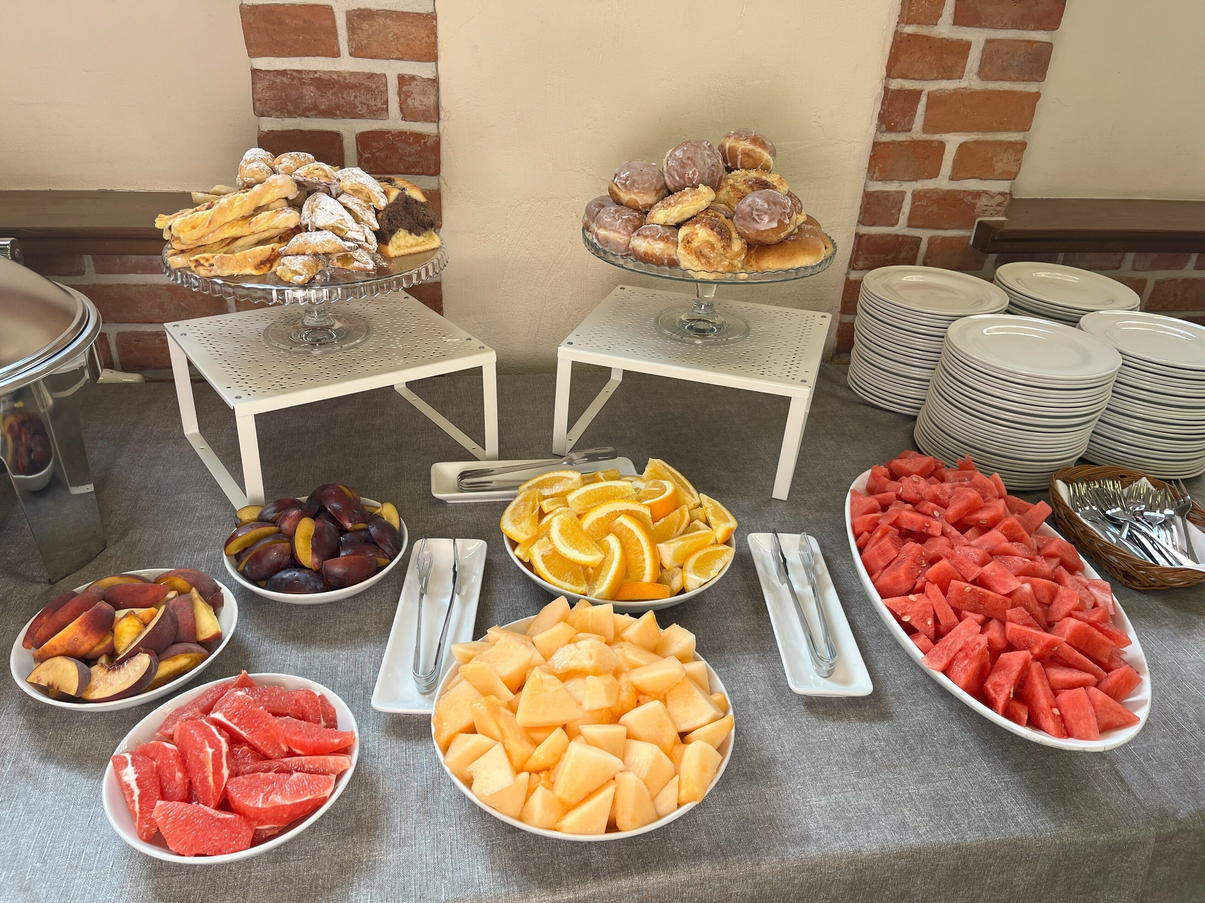A buffet table with various fruits and pastries.
