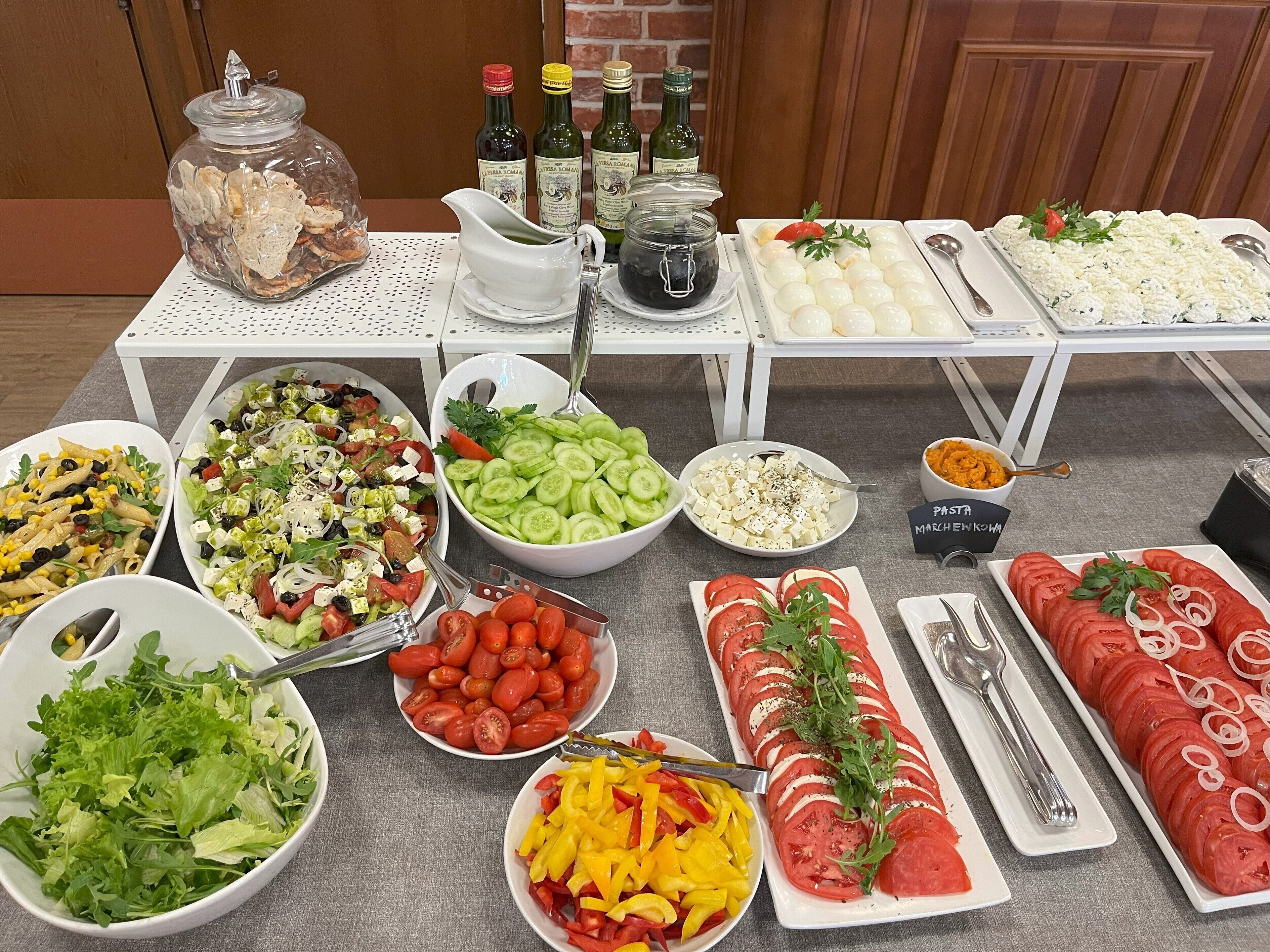 Ein reichhaltiges Buffet mit verschiedenen Speisen, darunter Salate, Tomatenscheiben und Käse.