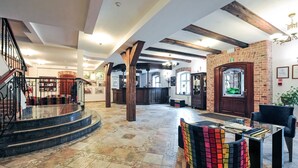 Un amplio vestíbulo con una escalera de mármol, una mesa de recepción y un área de descanso con sillas de colores.