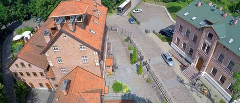 An aerial view of a courtyard with buildings, a paved area, and surrounding greenery.