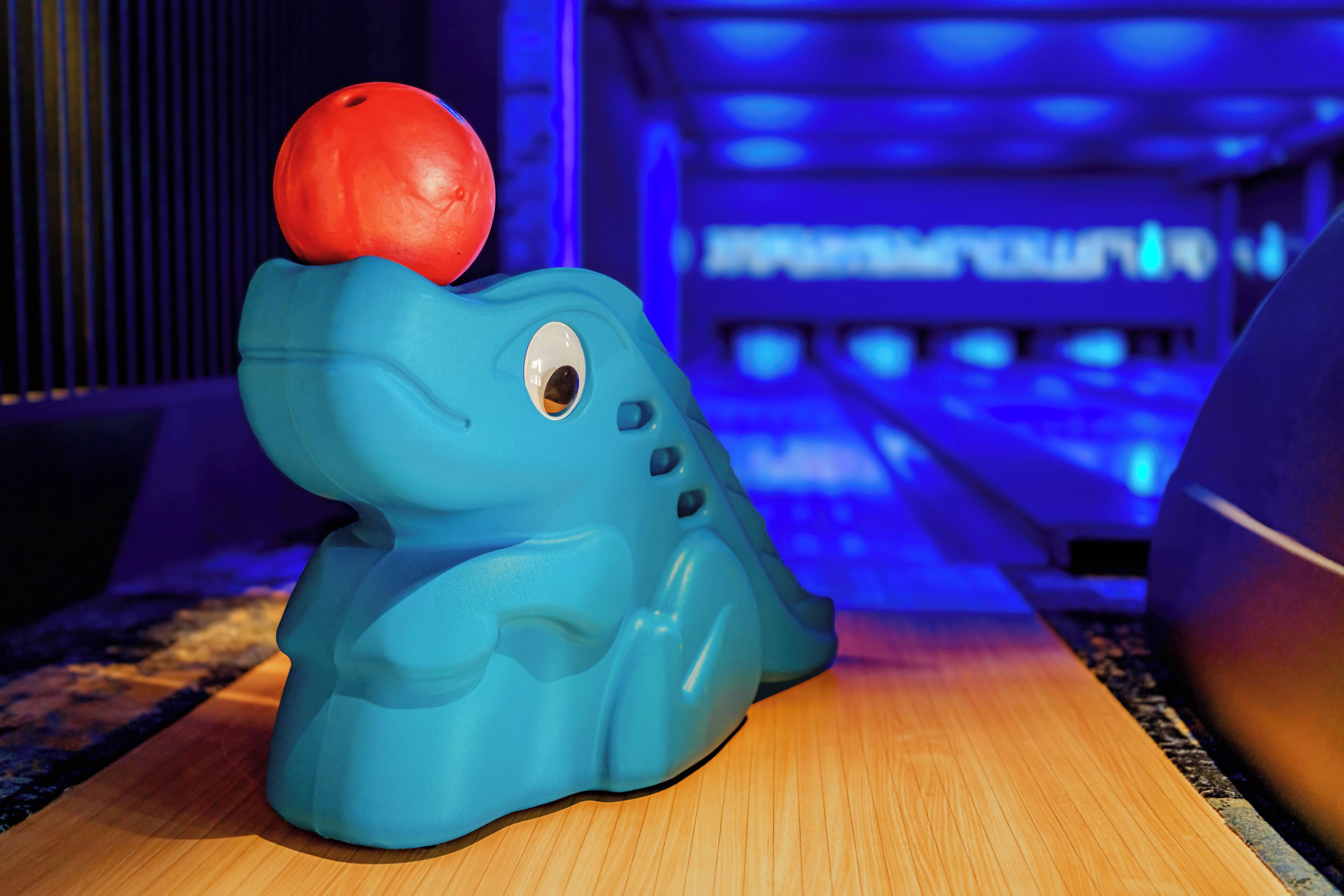 A blue elephant-shaped object with a red ball on top, placed on a wooden surface.