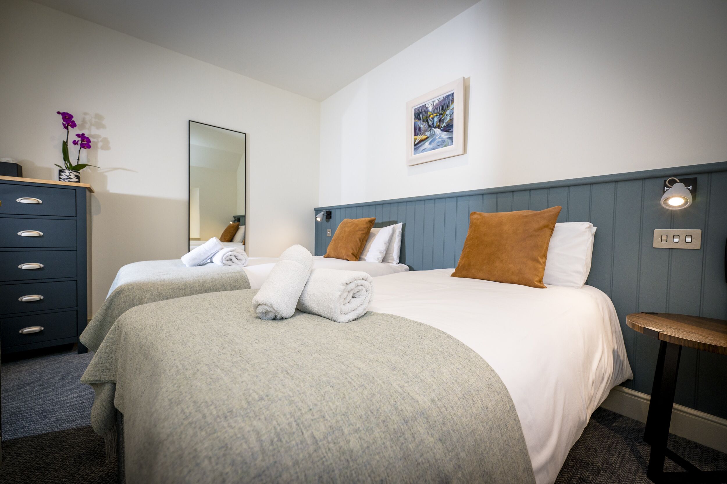 Una habitación de hotel con dos camas, un aparador, un espejo y un cuadro en la pared.