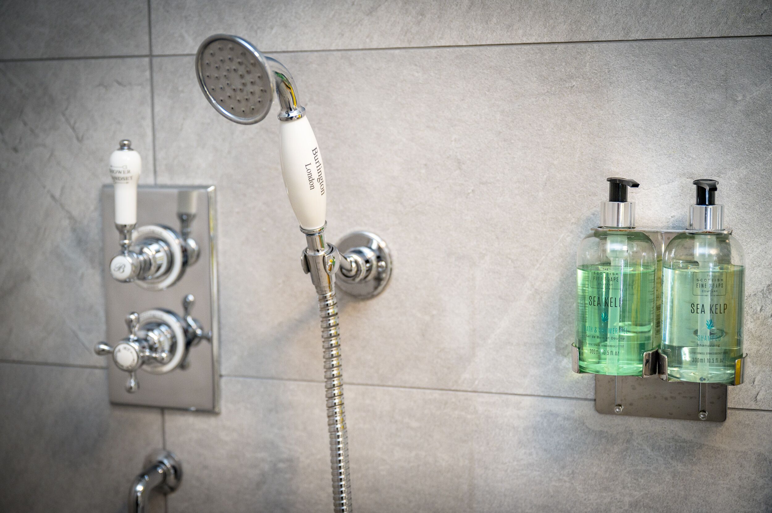 Une salle de bain équipée d’une douche, d’un pommeau de douche et de deux bouteilles de savon aux algues marines.