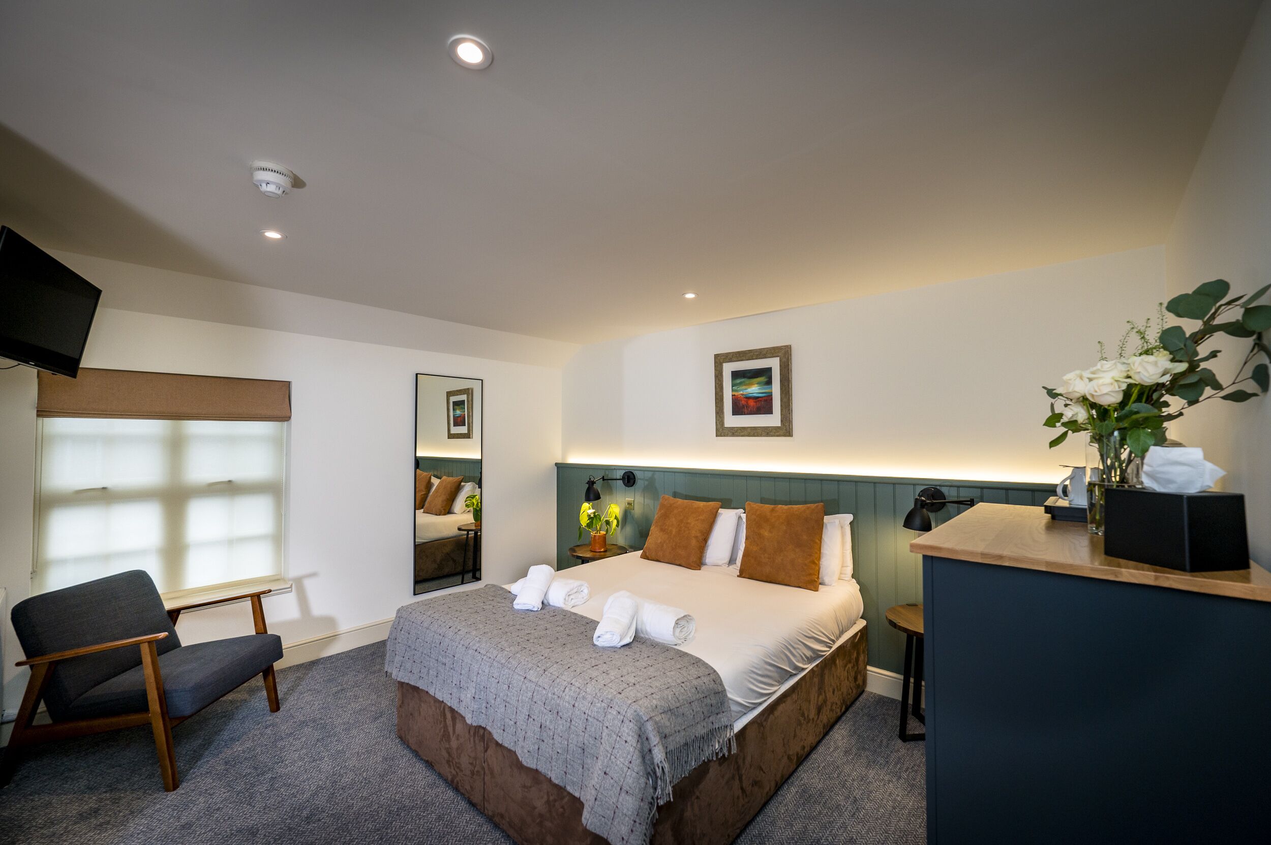 Una habitación de hotel con una cama, una silla, un escritorio, un televisor y una ventana.