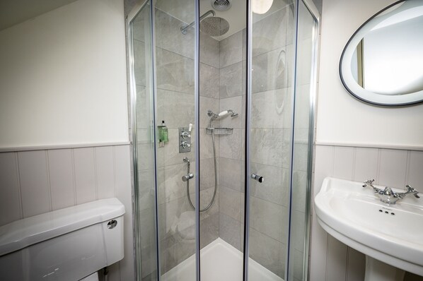 A modern bathroom with a glass-enclosed shower, a white sink, and a mirror.