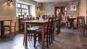 Un restaurante con mesas y sillas de madera, paredes de piedra y una chimenea de piedra.