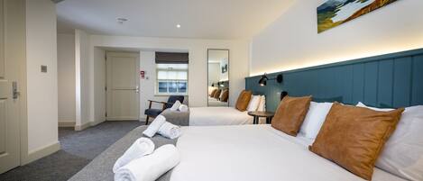 Habitación de hotel con dos camas, un espejo grande, un cuadro en la pared y vista al pasillo.