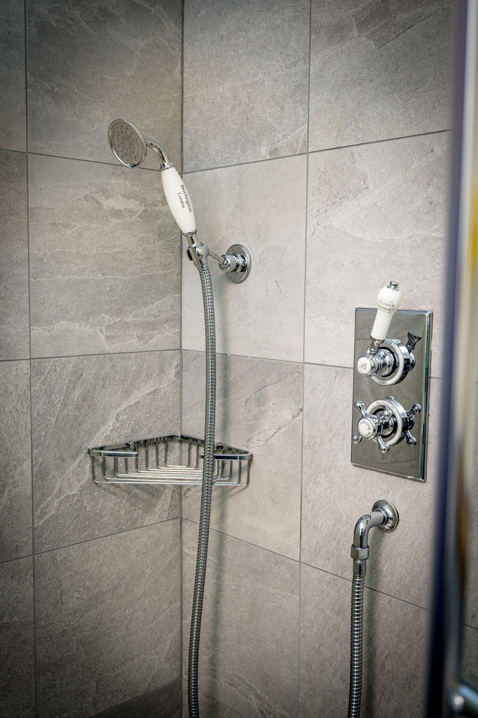 Une douche équipée d’un pommeau de douche à main, d’un robinet mural et d’un receveur de douche en chrome.