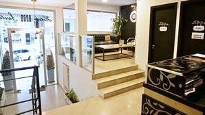 Een hotel receptie met een bank, een bijzettafeltje en een trap naar een verdieping.