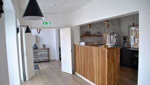 A modern kitchen area with wooden counters, a coffee machine, and shelves with bottles.