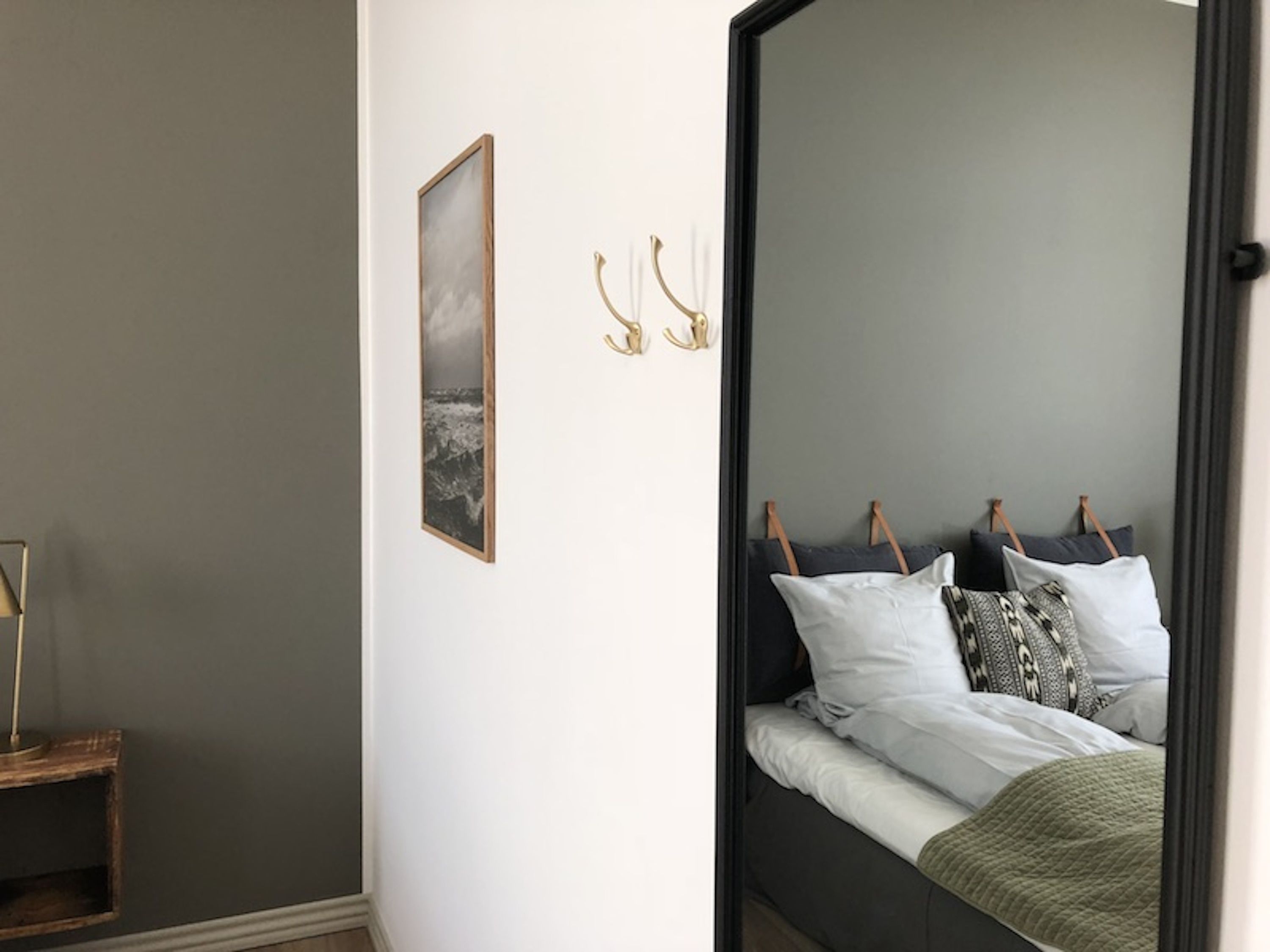 Una camera da letto con un letto, un comodino, un quadro incorniciato e uno specchio.