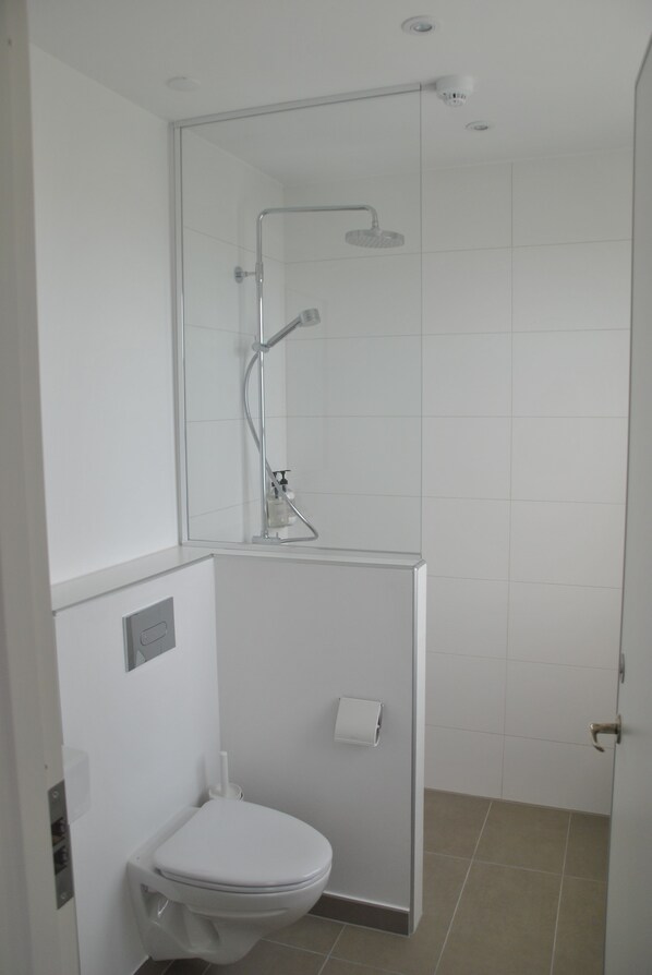 Un baño moderno con ducha de vidrio, inodoro y perchero para toallas.