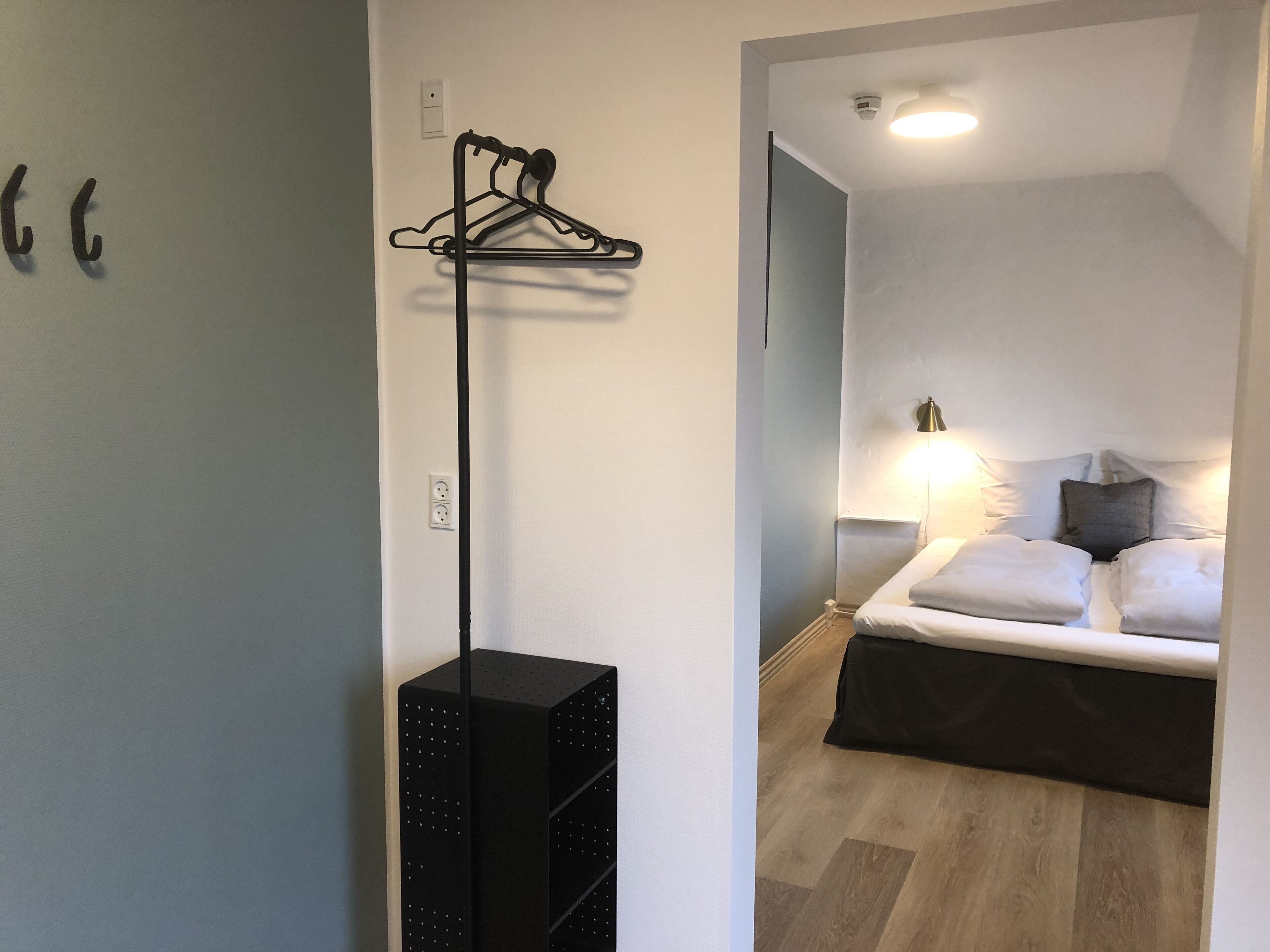 Ein Hotelzimmer mit Bett, Nachttischlampe und einer schwarzen Ablage an der Wand.