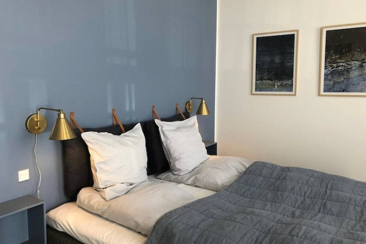 Une chambre à coucher avec un lit, deux lampes de chevet, une table de chevet et deux tableaux encadrés accrochés au mur.