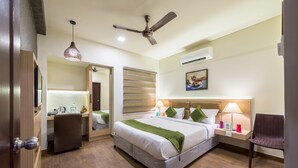 Ein Hotelzimmer mit Bett, Schreibtisch, Stuhl und Deckenventilator.