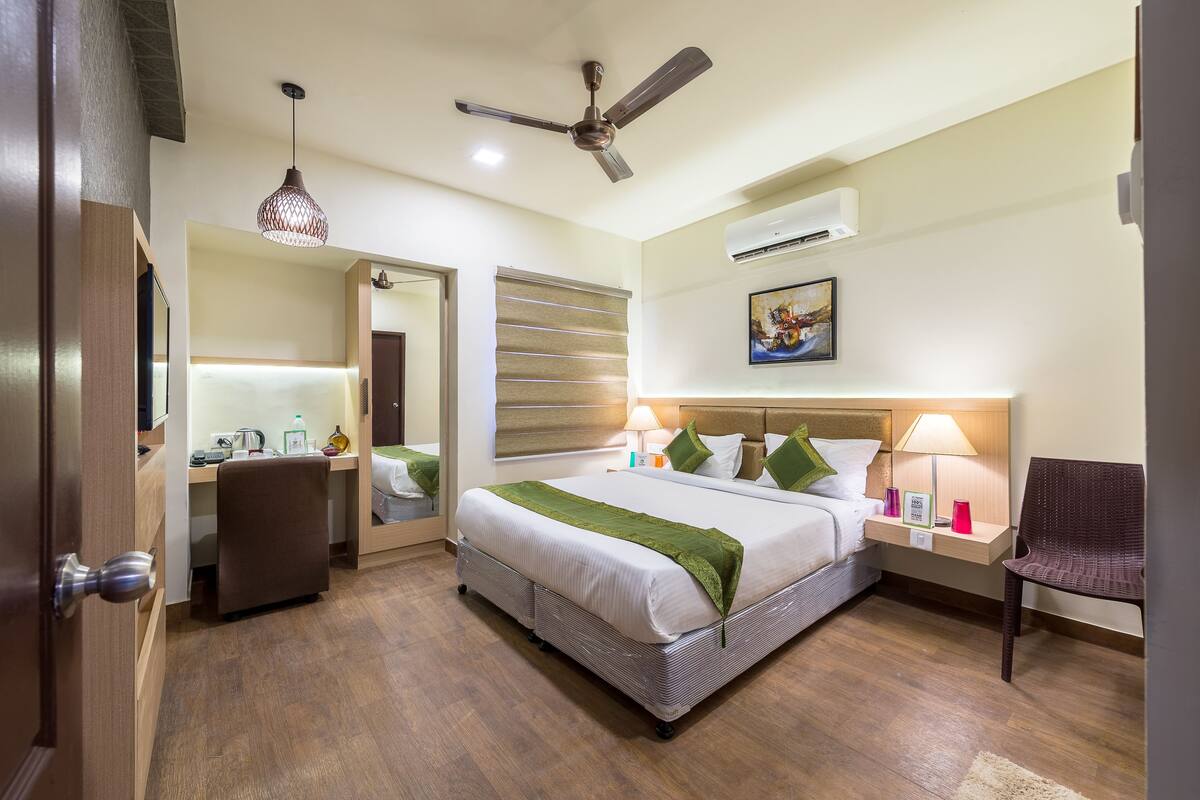 Une chambre d’hôtel équipée d’un lit, d’un bureau, d’une chaise et d’un ventilateur de plafond.