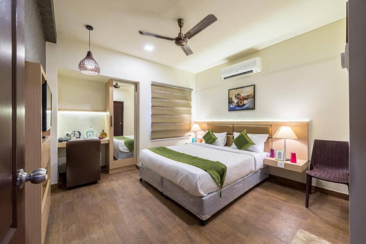 Une chambre d’hôtel équipée d’un lit, d’une table de chevet, d’une chaise, d’un bureau et d’un ventilateur de plafond.