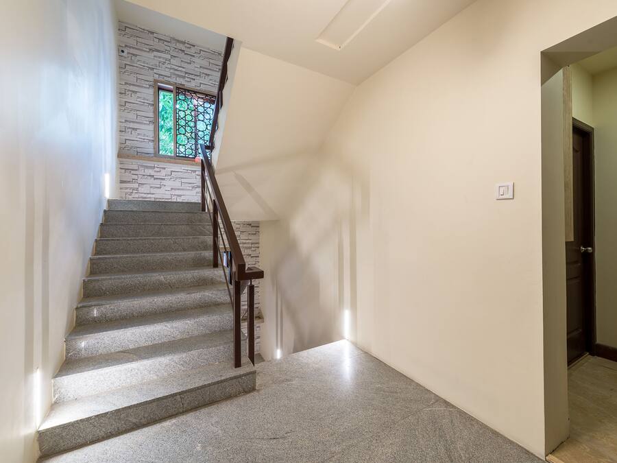Un escalier avec une rampe en bois, un mur orné d’un motif texturé et une porte en bas.
