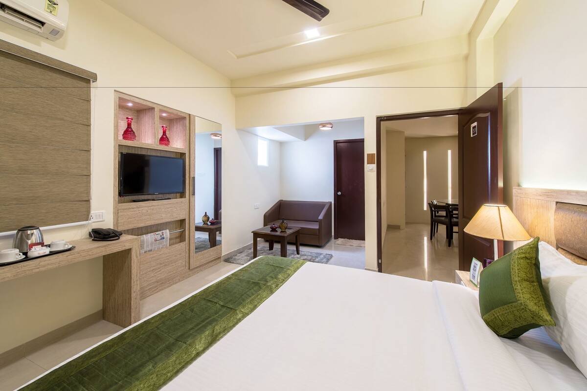 Une chambre d’hôtel comprenant un lit, un bureau avec une télévision, une chaise, une table à manger et une lampe.